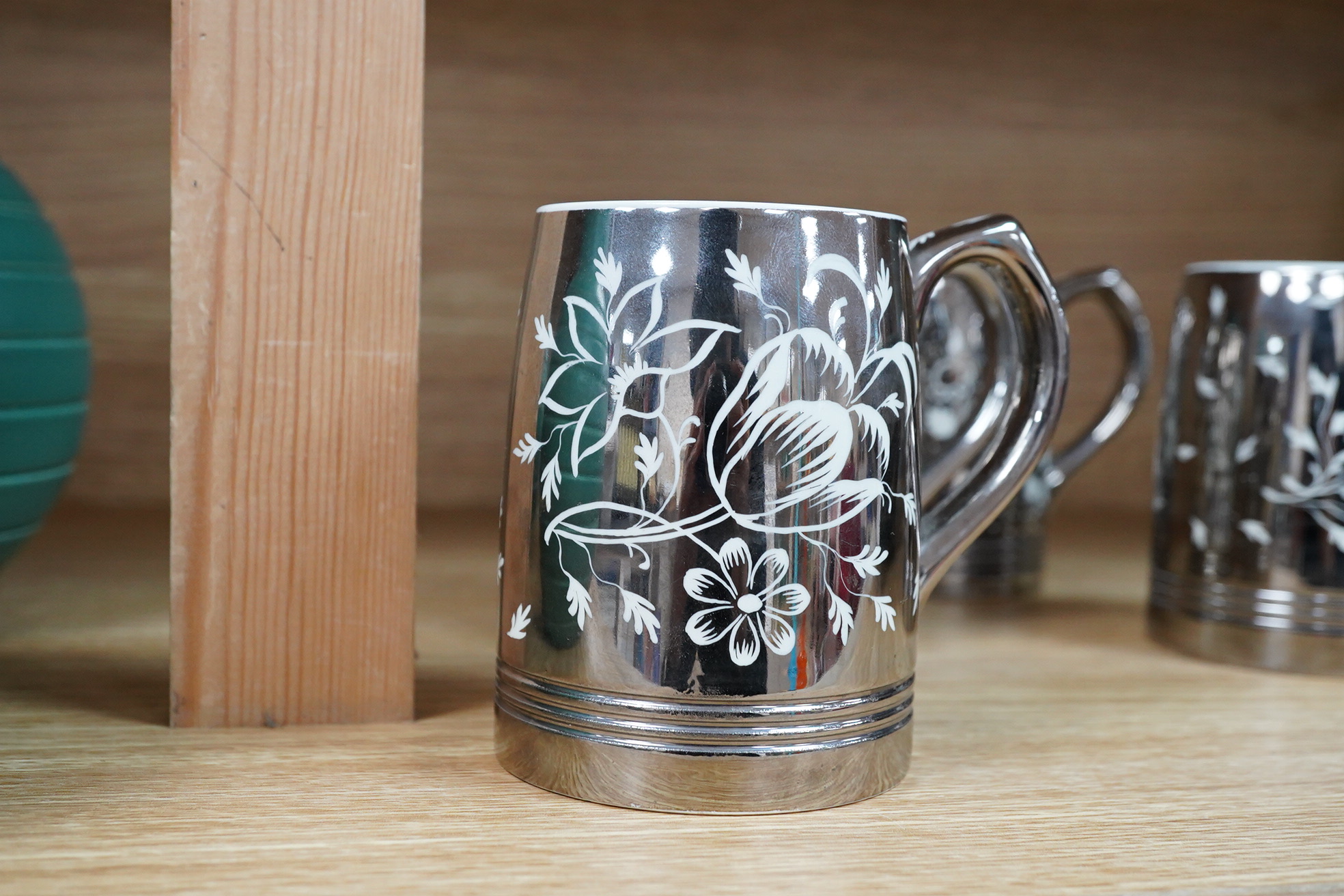 Keith Murray for Wedgwood, a set of four silvered mugs, decorated by Millicent Taplin, largest 10cm high